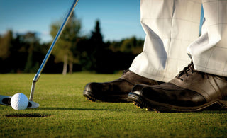 Golfer stood at the address of a golf ball with a golf putter