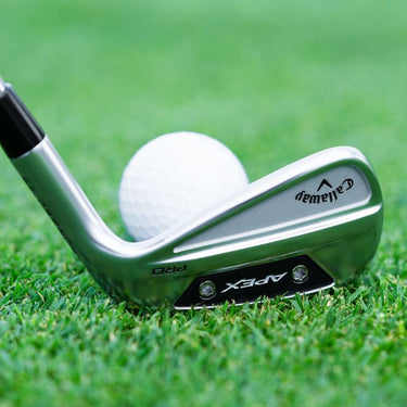 Callaway Apex Pro 24 Golf Iron at the address of a golf ball on a fairway. Angle is from behind the the club head.