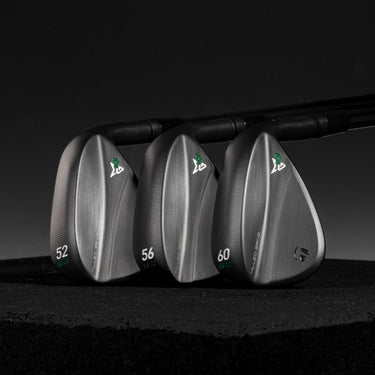 Three TaylorMade Milled Grind 4 Black Golf Wedges lined up showing the back of the club head on a dark black background