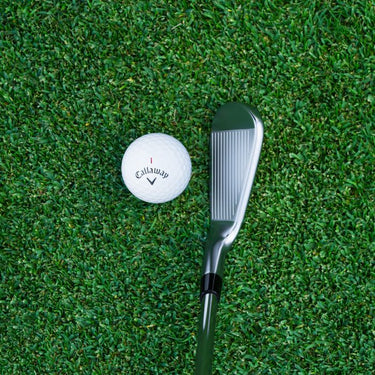 Callaway Apex Pro 24 Golf Iron being shown from above both the club head and a callaway golf ball. The club is at the address position on a fairway.