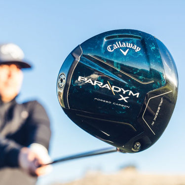 Callaway Golf Paradym X Driver being held up by a golfer so the sole of the club head is visible, golfer stood in background with sky behind